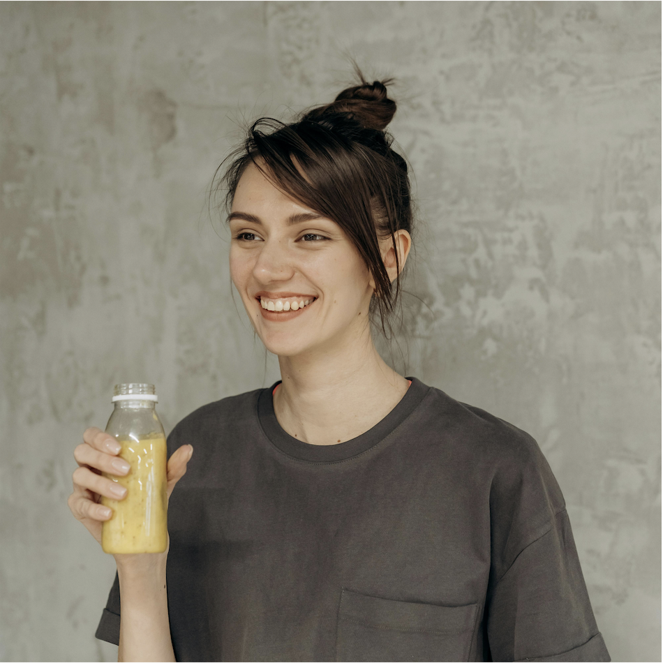 Smiling woman holding a yellow smoothie bottle, creator-style UGC photo for influencer marketing campaigns